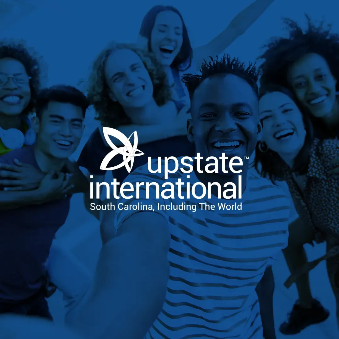 Upstate International logo and tagline South Carolina, Including The World over a blue-tinted photo of a diverse group of smiling young people